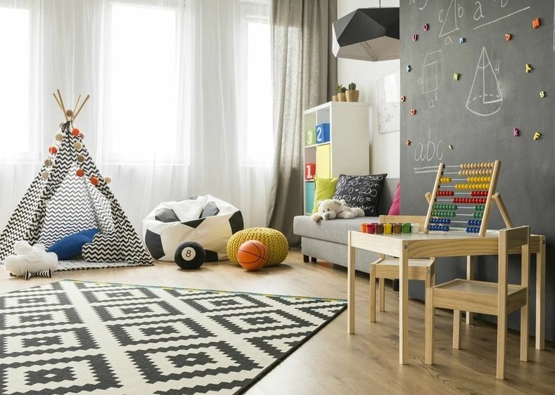 kids room decor, patterned rug, wood table, teepee & toys in front of white curtains